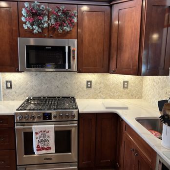 Modern kitchen with wood cabinets, stainless steel gas range, and white countertops