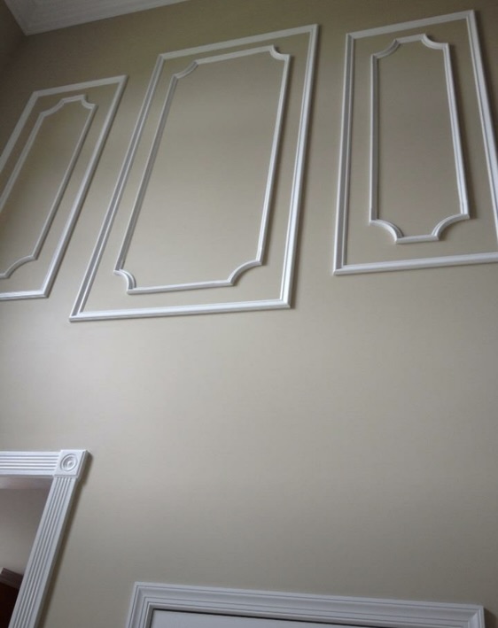 Decorative wall panels with white trim and recessed frames on cream colored wall