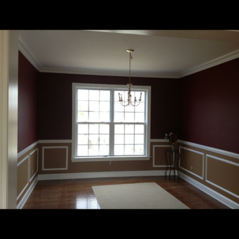 Elegant dining room with burgundy walls, white wainscoting, large window, and chandelier
